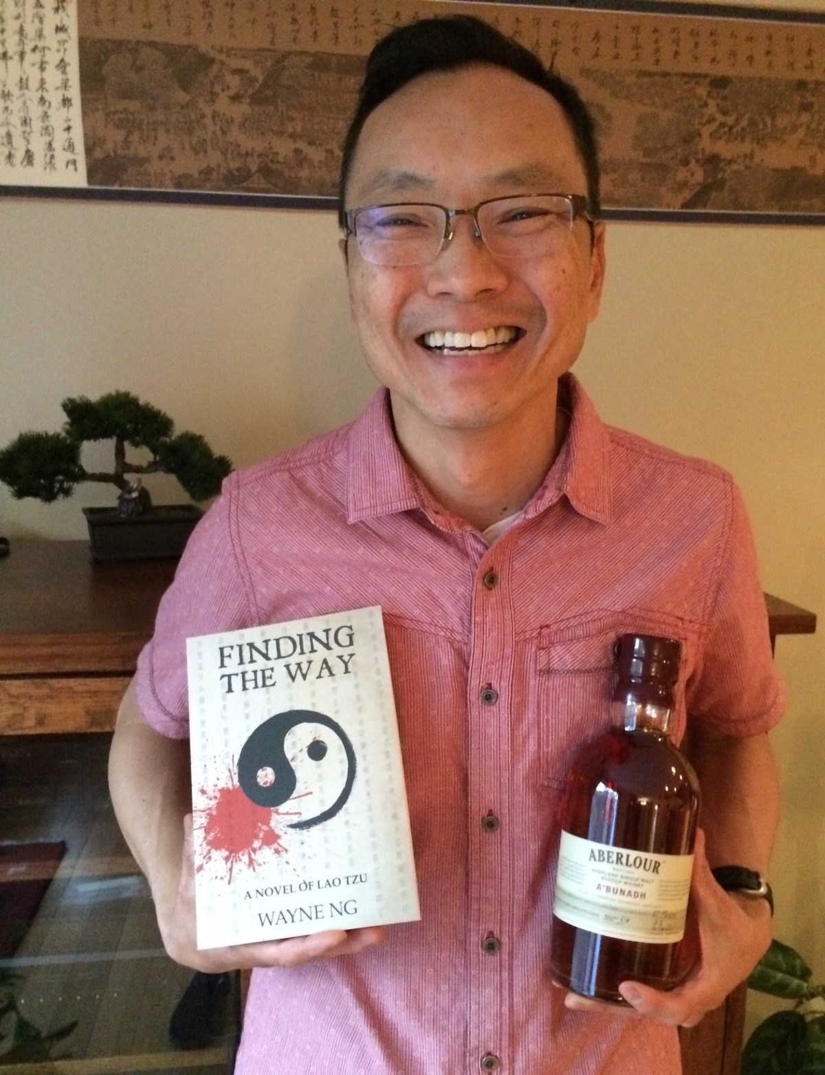 Wayne Ng with book and bottle of scotch