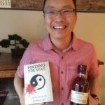 Wayne Ng with book and bottle of scotch