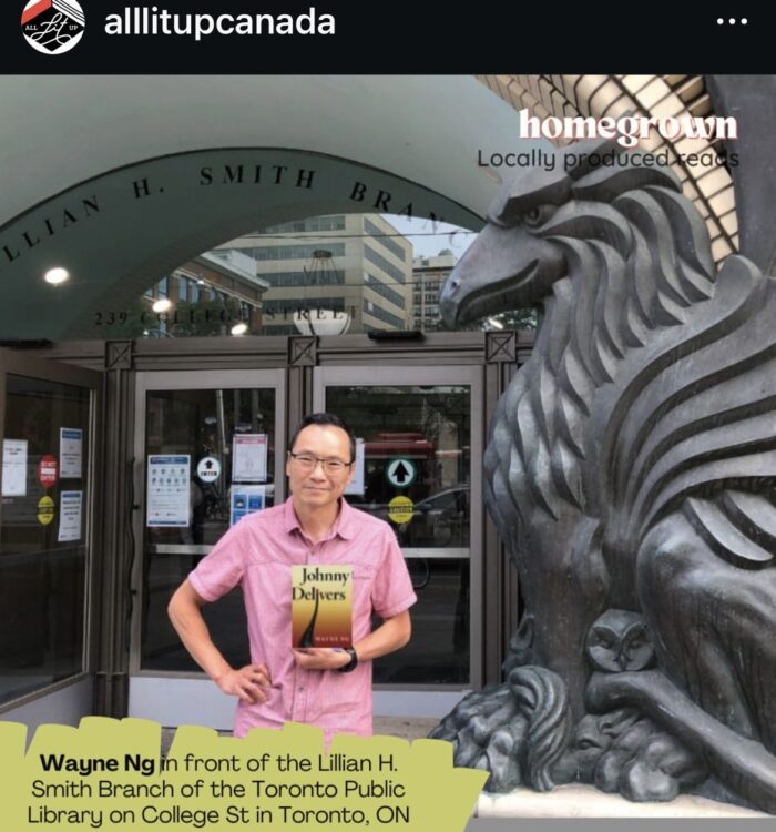 Wayne Ng is pictured holding a copy of JOHNNY DELIVERS before the Lillian H. Smith Branch of the Toronto Public Library on College St, Toronto