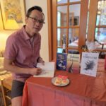 Wayne Ng signing books at the Hawesbury Book Club. With a plate of pagoda cookies. Books: Letters From Johnny, Johnny Delivers and The Family Code.