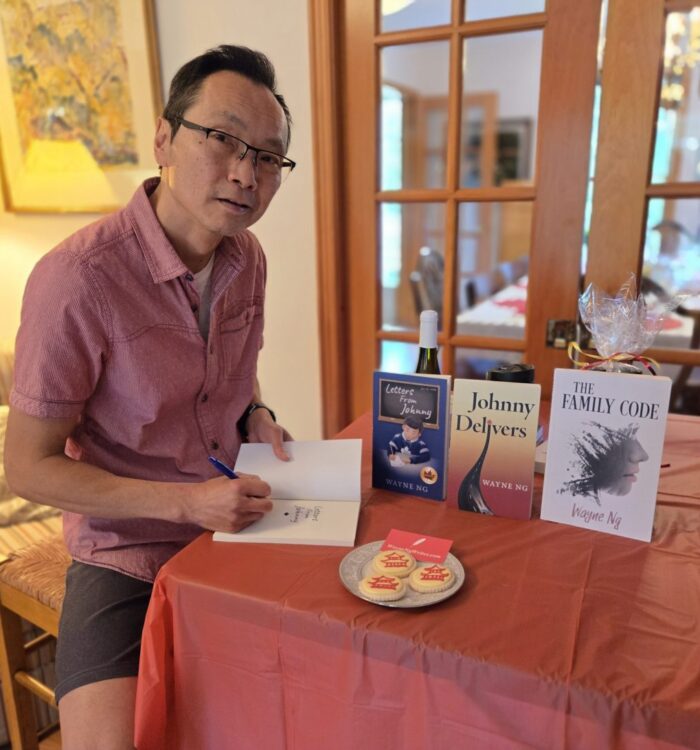 Wayne Ng signing books at the Hawesbury Book Club. With a plate of pagoda cookies. Books: Letters From Johnny, Johnny Delivers and The Family Code.