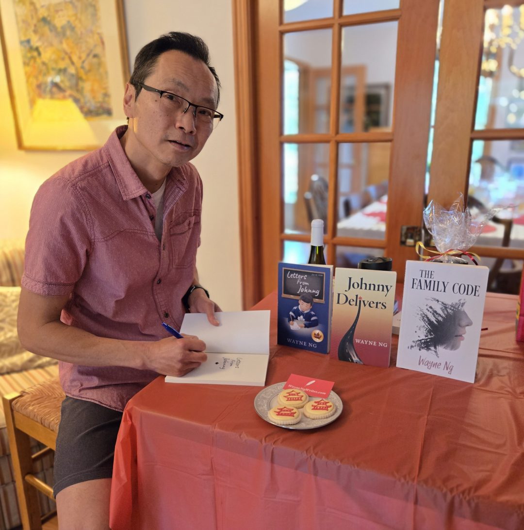 Wayne Ng signing books at the Hawesbury Book Club. With a plate of pagoda cookies. Books: Letters From Johnny, Johnny Delivers and The Family Code.
